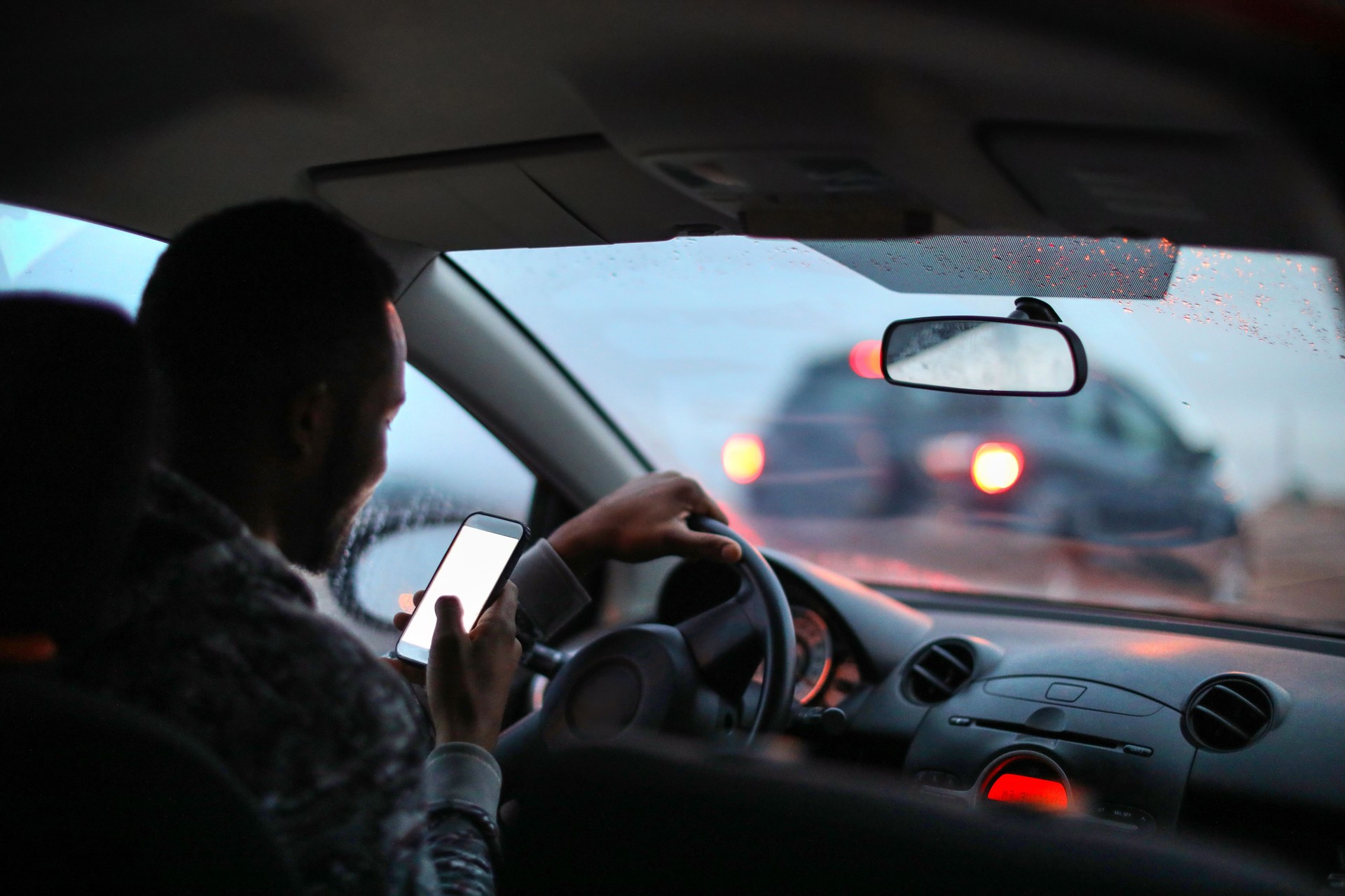 Man using his phone while driving in the rain.