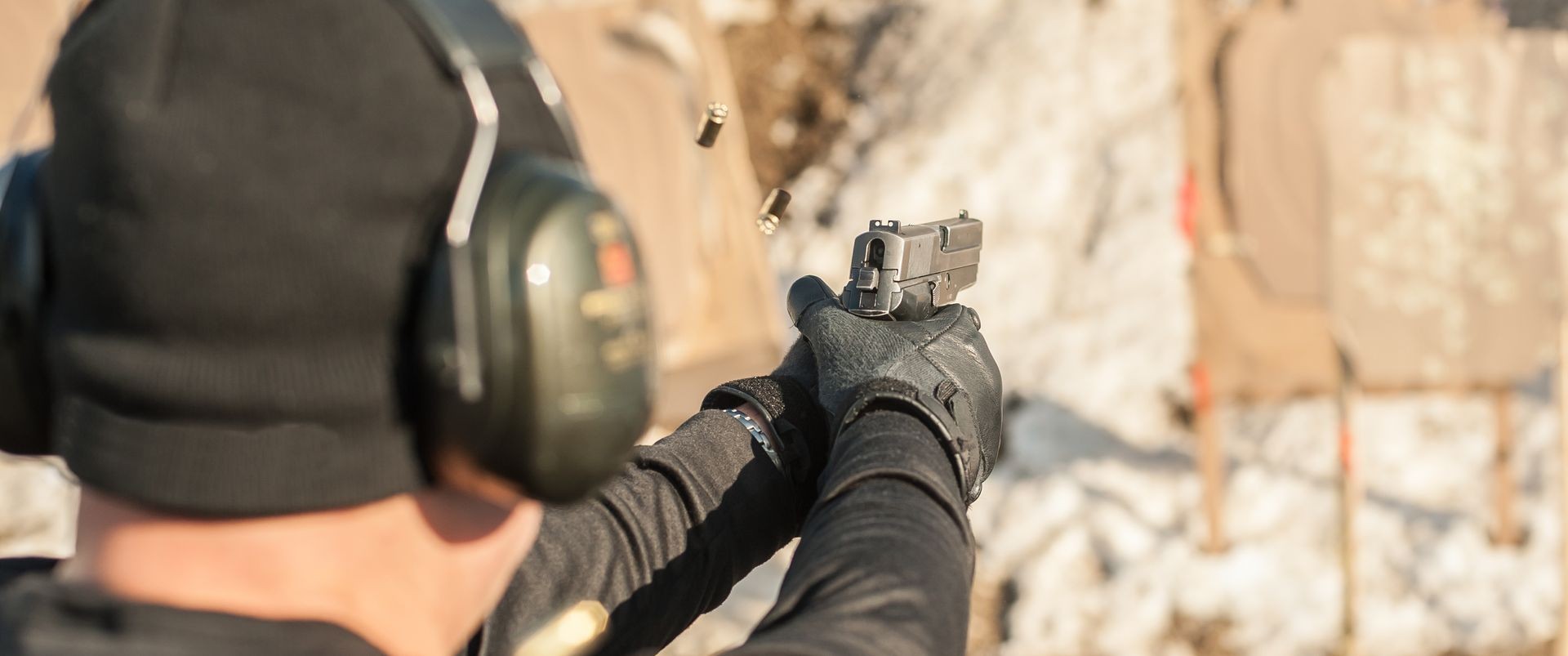 Detail view of shooter holding gun in hand and shooting, close up. Shooting range