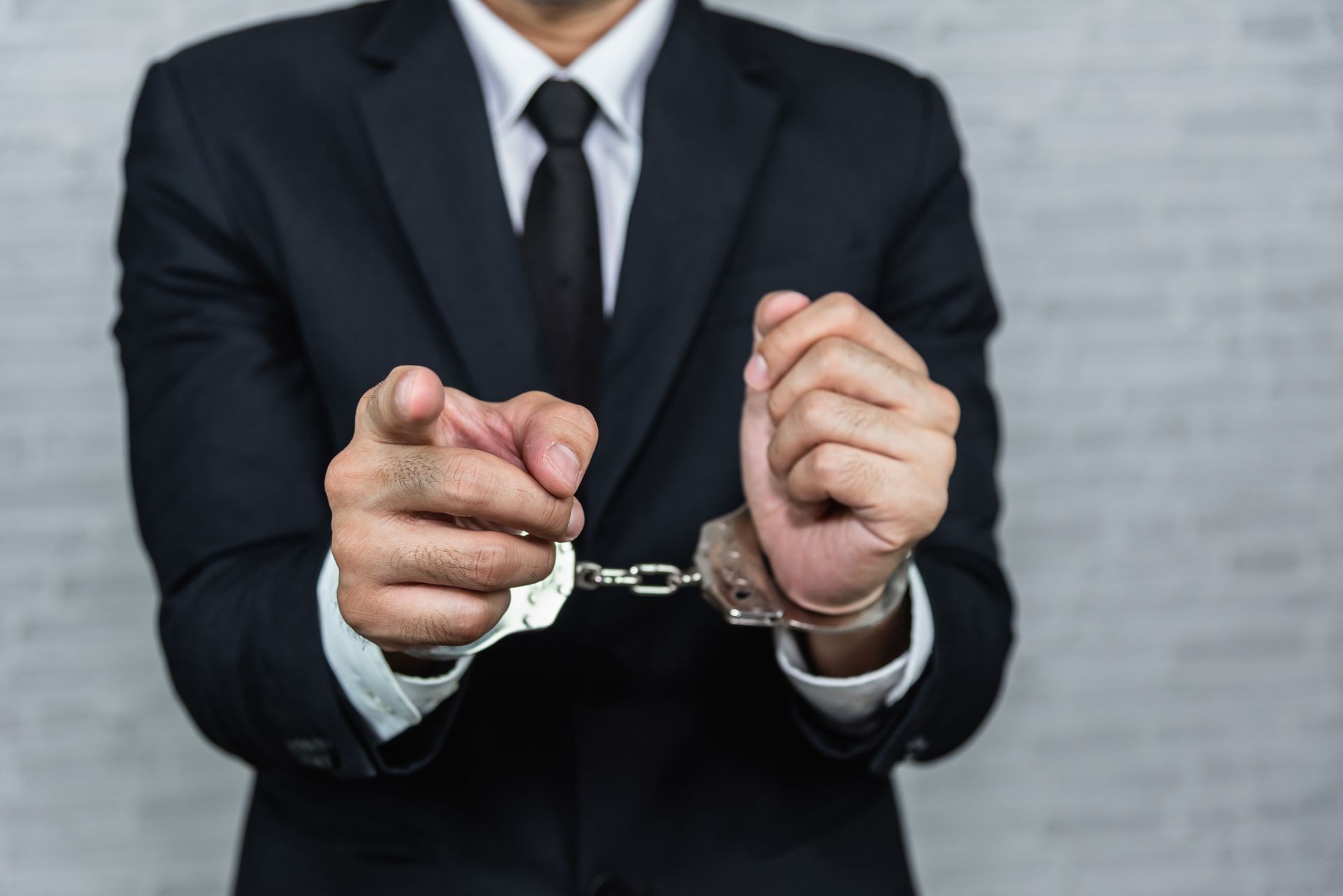 businessman in handcuffs arrested isolated on gray background