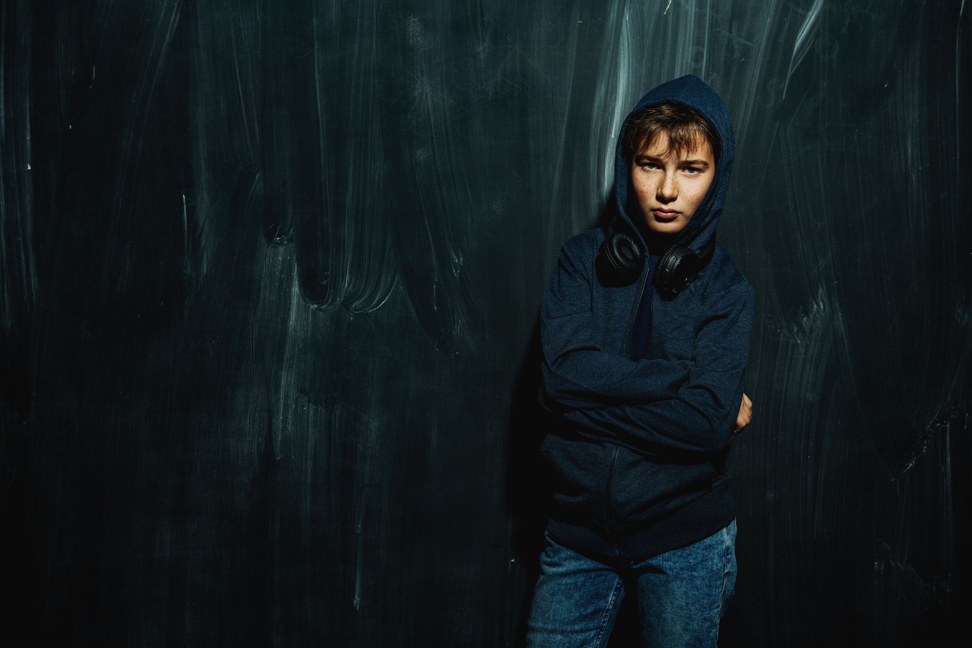 A portrait of a boy wearing casual clothes posing near a black wall. Fashion for teenagers.